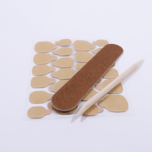 Kit de pose pour faux ongles press on gel avec une lime, deux feuilles de gels pads et un bâtonnet de buis, photographié en légère inclinaison sur fond blanc pour mettre en valeur les accessoires indispensables.